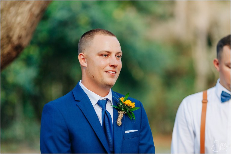groom smiles as he sees bride coming down the aisle at DIY Florida Barn Wedding