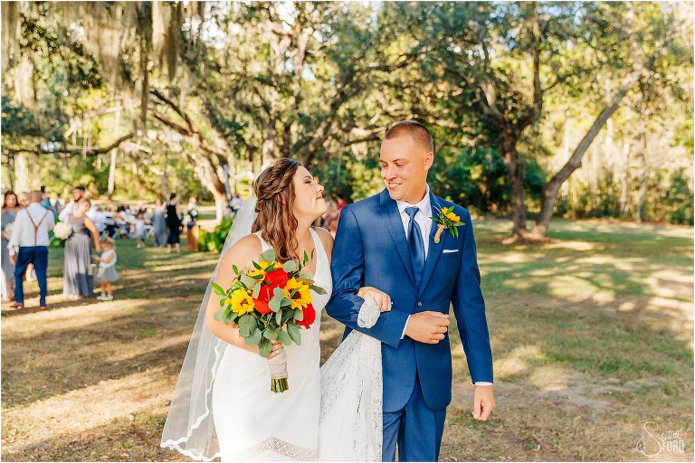 bride and groom smile giddily at each other as they leave DIY Florida Barn Wedding ceremony arm in arm