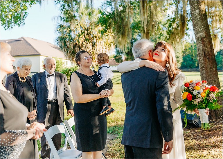 bride gives father emotional hug as he presents her to groom at elegant backyard elopement ceremony