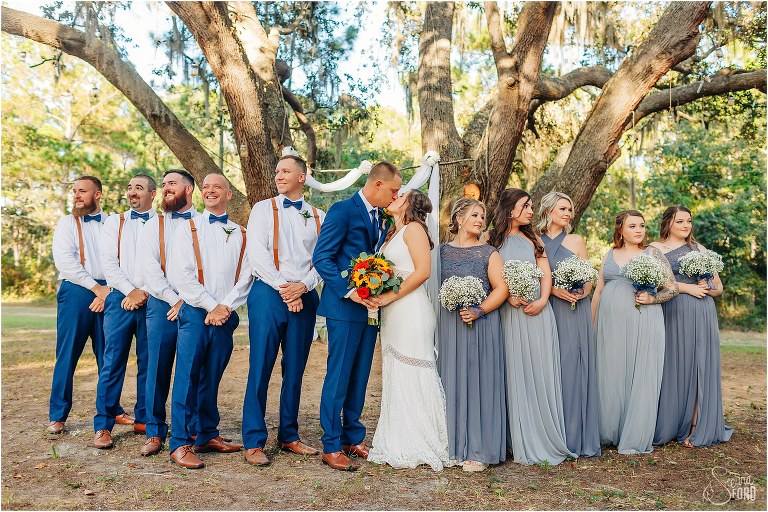 bride & groom kiss surrounded by their wedding party at DIY Florida Barn Wedding