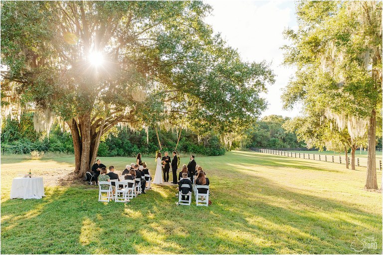 loved ones look on as bride & groom exchange vows at elegant backyard elopement ceremony