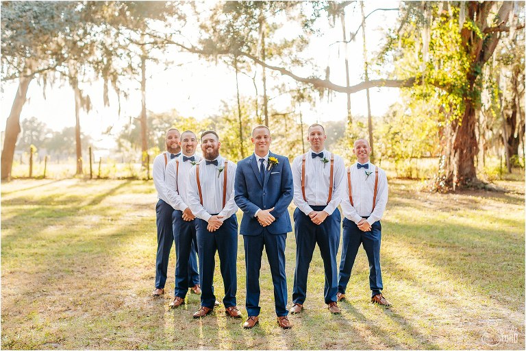 groom stands with groomsmen as sun sets on DIY Florida Barn Wedding