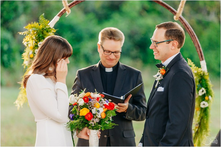 bride wipes away tears during emotional elegant backyard elopement ceremony