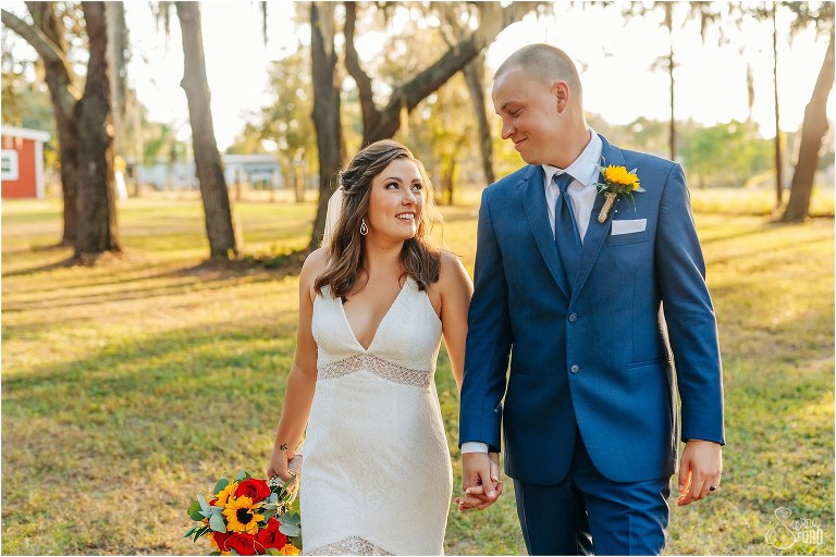 bride smiles up at her groom as they stroll together at sunset at DIY Florida Barn Wedding