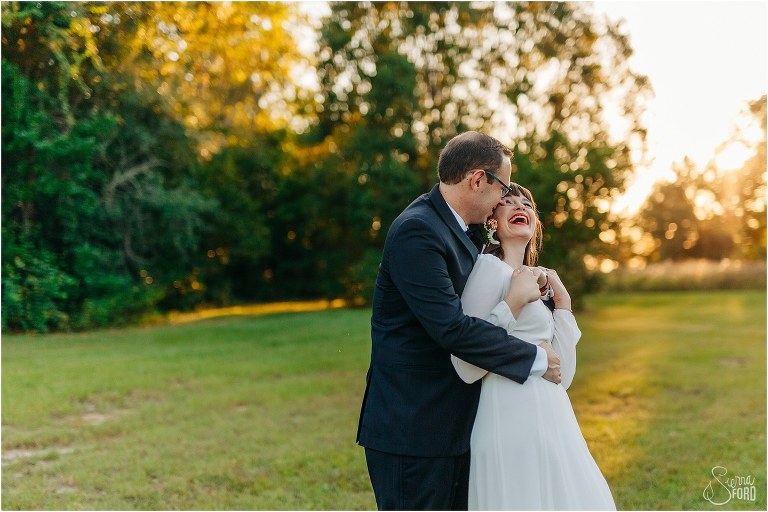 bride laughs as groom hugs her from behind at elegant backyard elopement