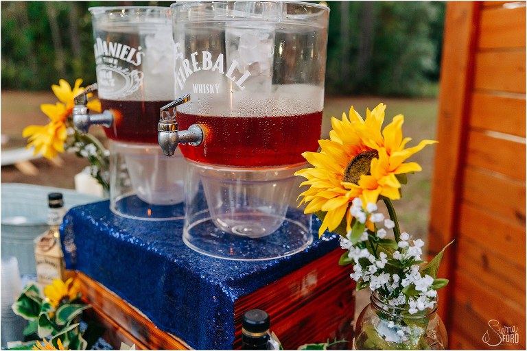 big sunflowers surround FIreball and Jack Daniel's whiskey dispensers at DIY Florida Barn Wedding reception