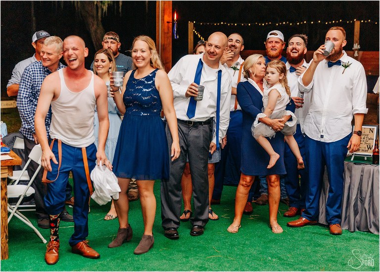 friends and family laugh and smile at groom's impressive garter retrieval dance at DIY Florida Barn Wedding reception