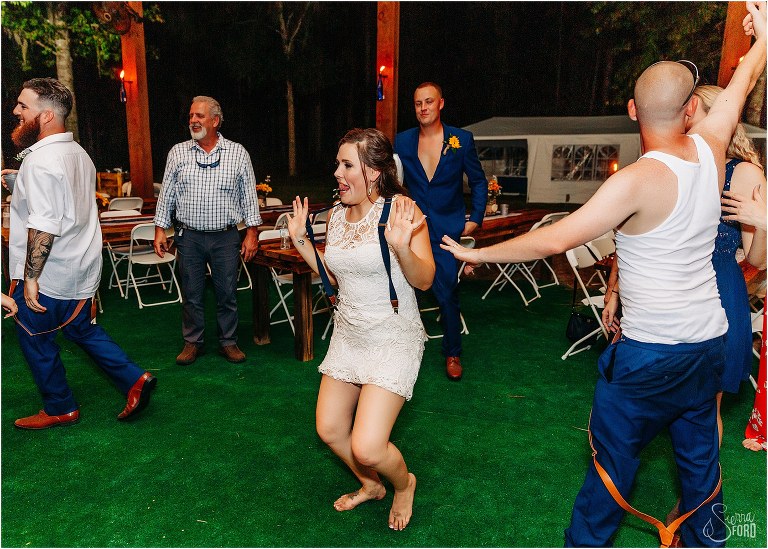 bride shows off her dance moves wearing groom's suspenders at DIY Florida Barn Wedding reception