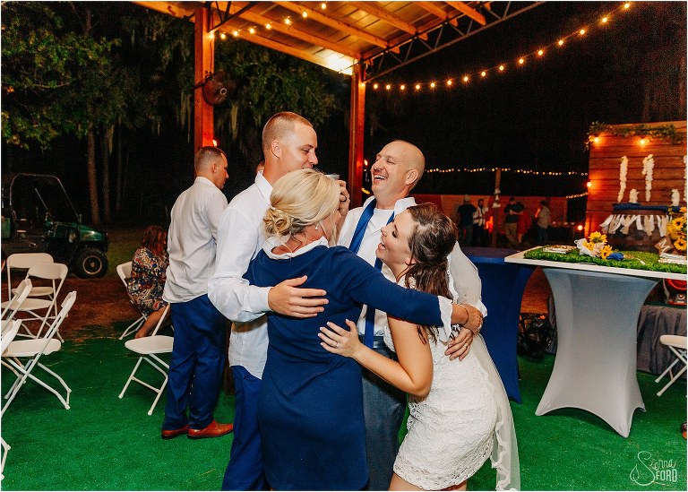 bride & groom group hug their family at DIY Florida Barn Wedding reception