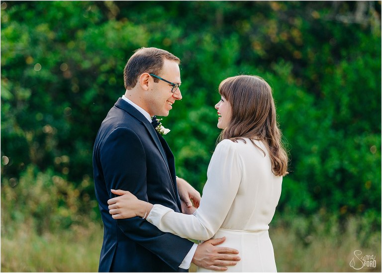 bride and groom laugh with each other during first look before elegant backyard elopement