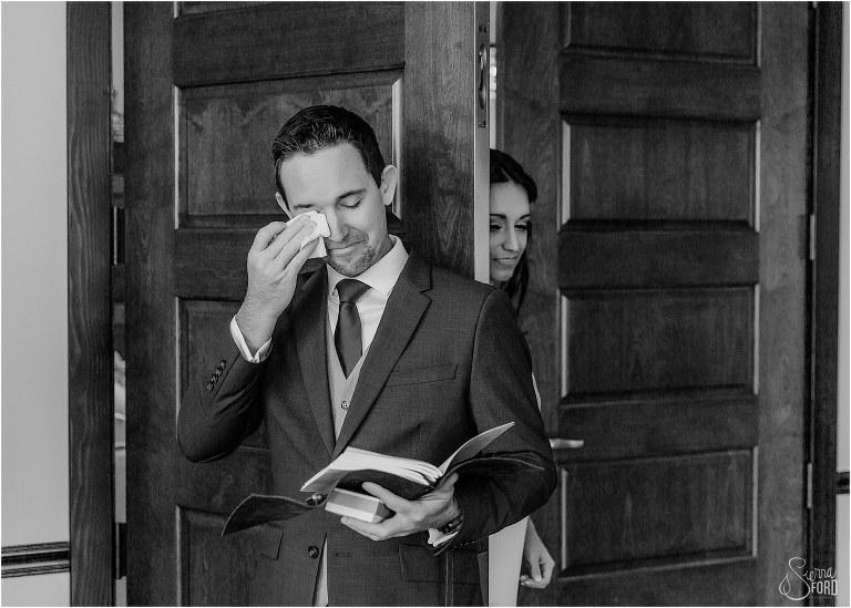 groom wipes tears away during emotional first touch before waterfront wedding