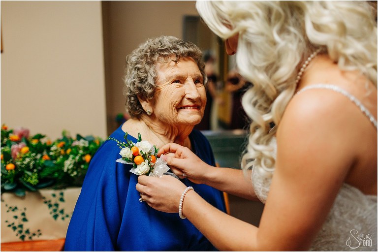 bride pins corsage onto grandmother's dress before Horsepower Ranch wedding