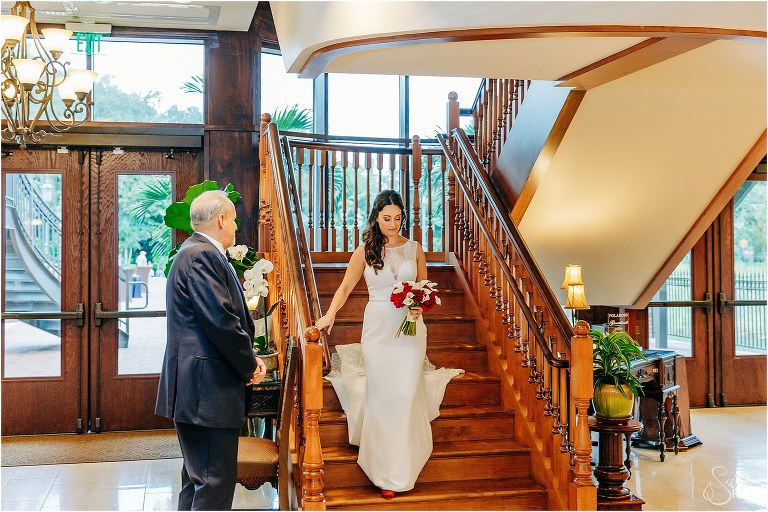 bride comes down stairs to meet father for waterfront wedding ceremony