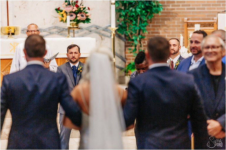 peek at the emotional groom as brothers walk bride down aisle at Horsepower Ranch wedding