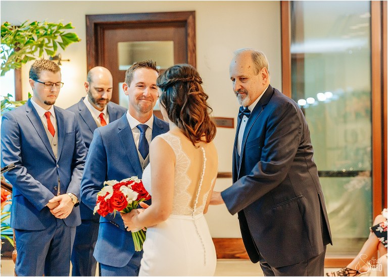 father gives daughter away to groom at waterfront wedding ceremony