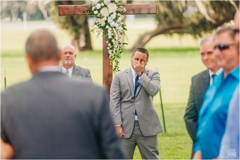 groom wipes tears from his eyes as bride comes down the aisle at Wildwood wedding