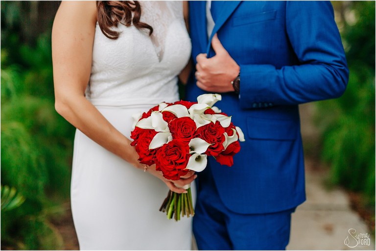 bride holds beautiful red and white bridal bouquet from Peddles at waterfront wedding
