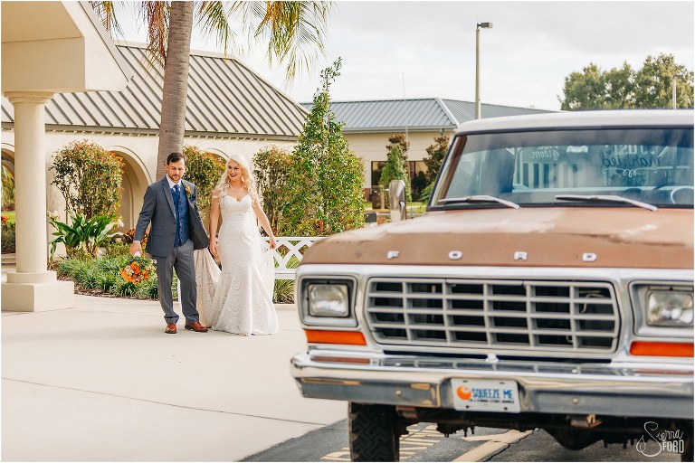 groom carries bride's train as they head to 1978 F-250 to head to Horsepower Ranch wedding reception