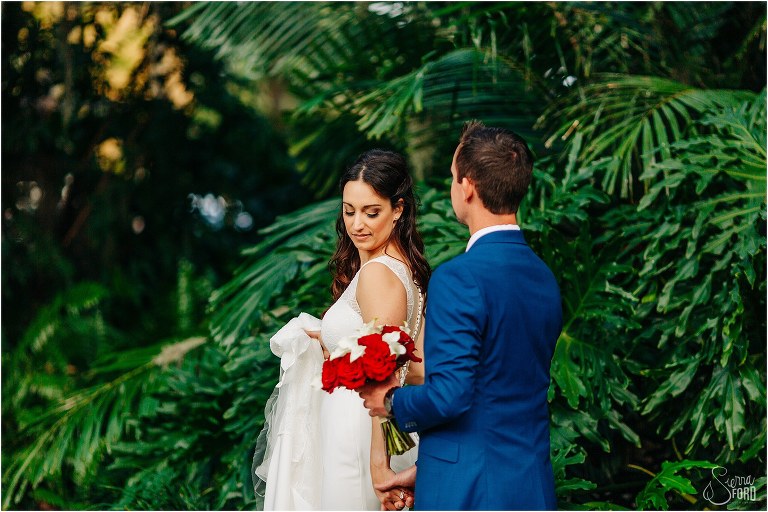 bride leads groom into greenery at waterfront wedding