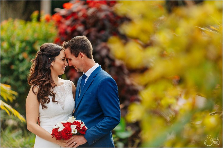 bride & groom forehead to forehead among greenery at waterfront wedding