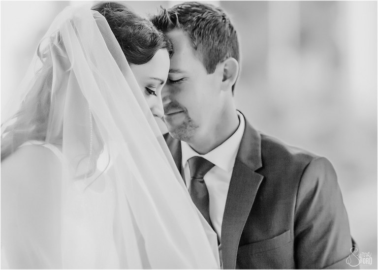bride & groom nuzzle up for private moment at waterfront wedding