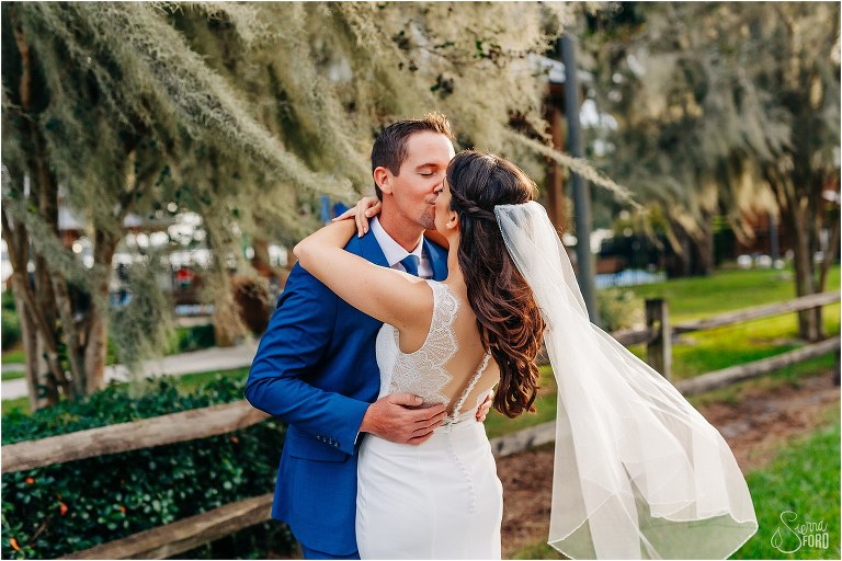bride leans back as groom goes in for deep kiss at waterfront wedding