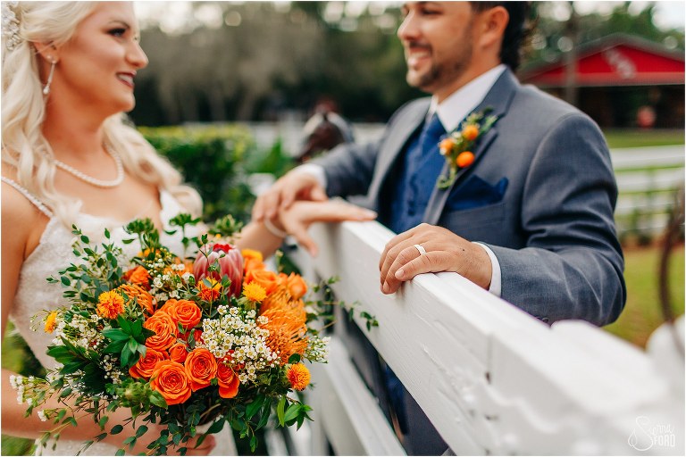 bride & groom flirt over picket fence at Horsepower Ranch wedding