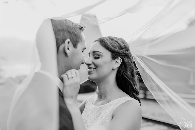 bride nuzzles groom under veil at waterfront wedding