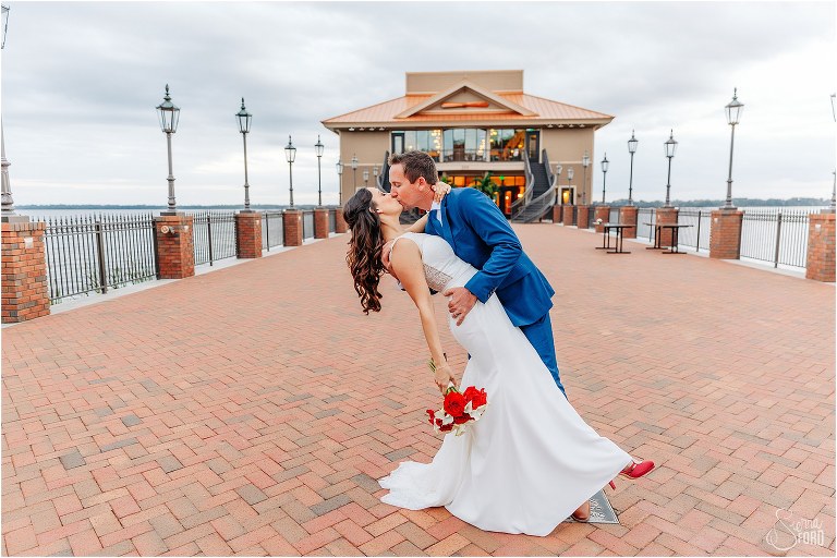 bride & groom dip kiss at end of pier at waterfront wedding