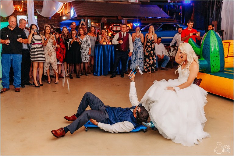 groom uses headlamp and roll cart to retrieve bride's garter at Horsepower Ranch wedding