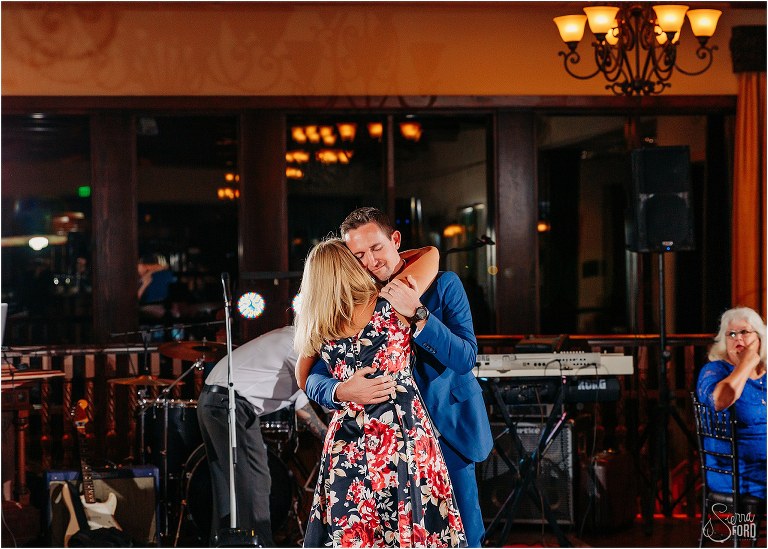 groom shares dance with his sister as tribute to their parents at waterfront wedding reception