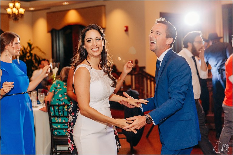 bride & groom laugh and dance together at waterfront wedding reception
