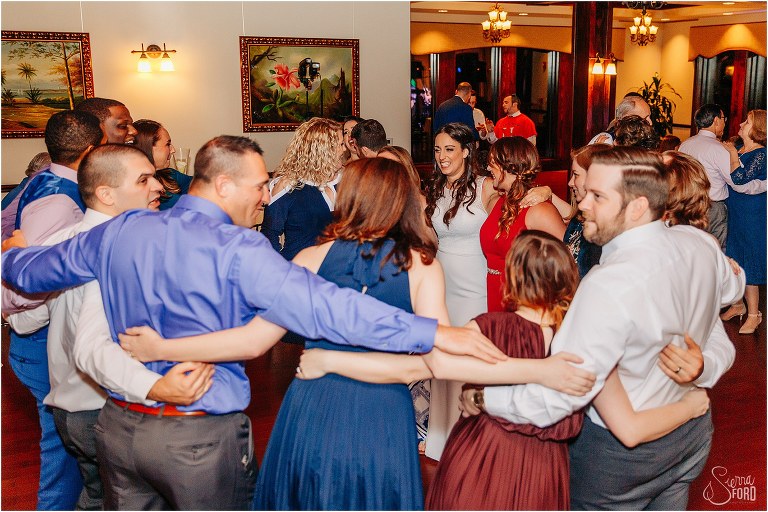 bride dances with huge group of friends at waterfront wedding reception