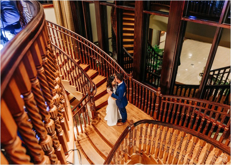 bride & groom share quiet moment on grand staircase at waterfront wedding reception