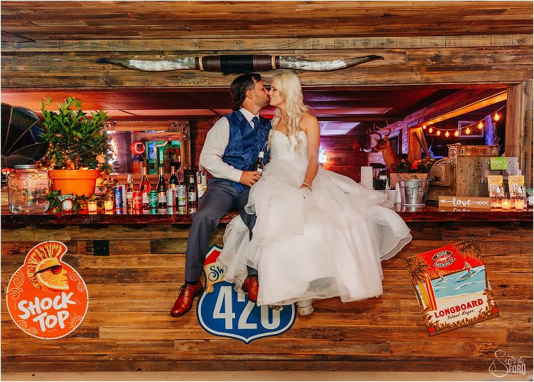 bride & groom kiss on top of the bar at Horsepower Ranch wedding reception