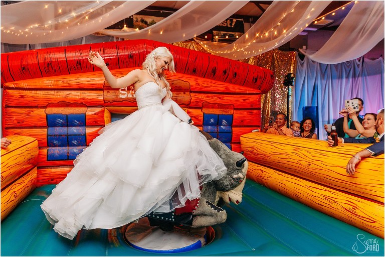 bride shows off skills at riding mechanical bull at Horsepower Ranch wedding