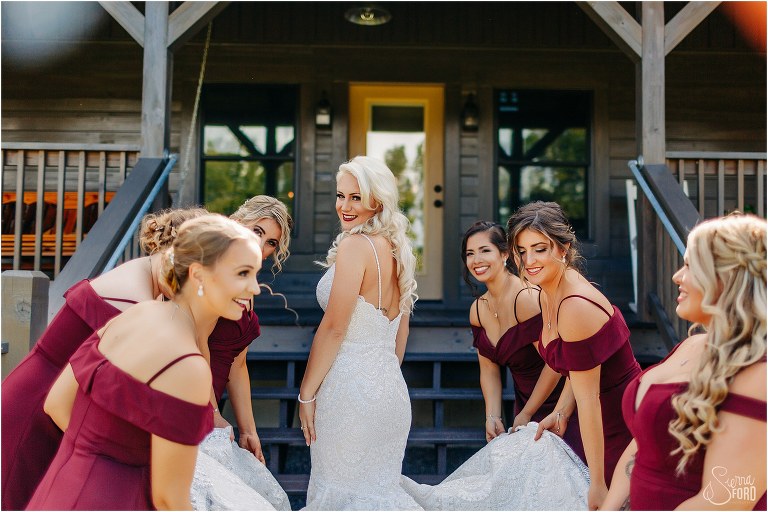 bridesmaids fluff out bride's train before Horsepower Ranch wedding