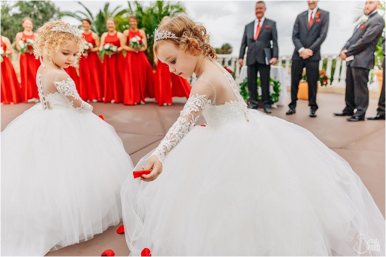 princess flower girls carefully distribute red rose petals down aisle at Mission Inn Resort wedding