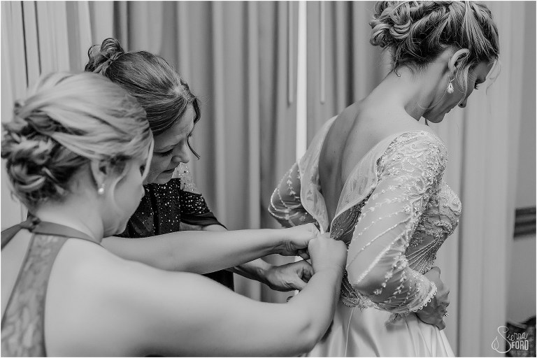 bride's mother & sister help button her Casablanca Bridal Gown before Mission Inn Resort wedding 