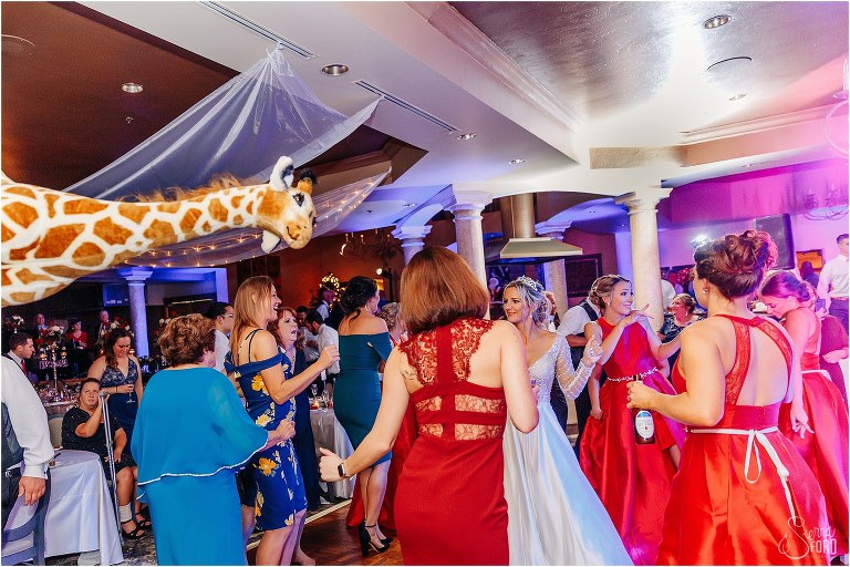 stuffed giraffe appears above the dancing crowd at Mission Inn Resort wedding reception