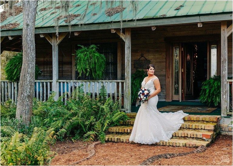 bride looks off into distance as dress trails down stairs behind her at Isola Farms wedding