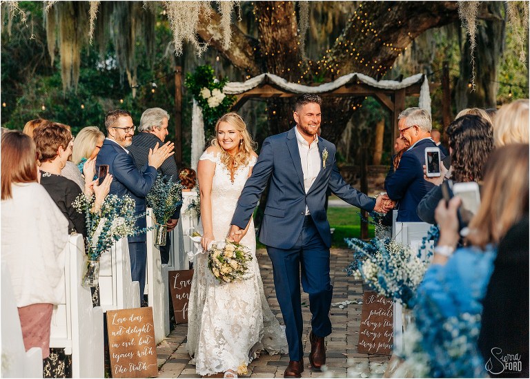 groom shakes hand of guest as they walk back down aisle at Ever After Farms wedding