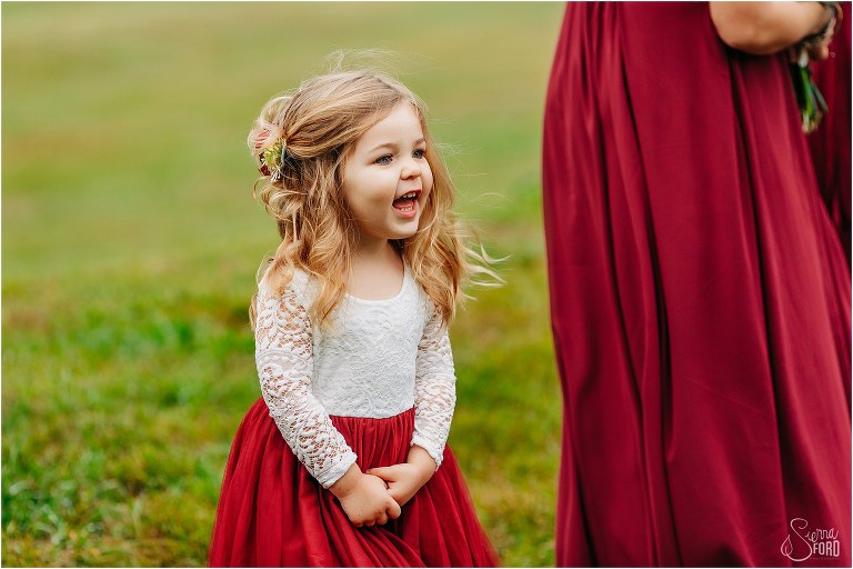flower girls looks at bride coming down aisle with huge grin at lakefront wedding ceremony