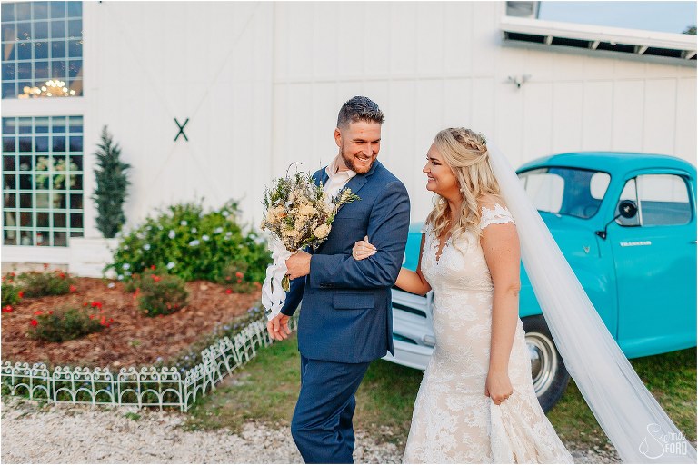 bride and groom walk arm in arm around barn at Ever After Farms wedding