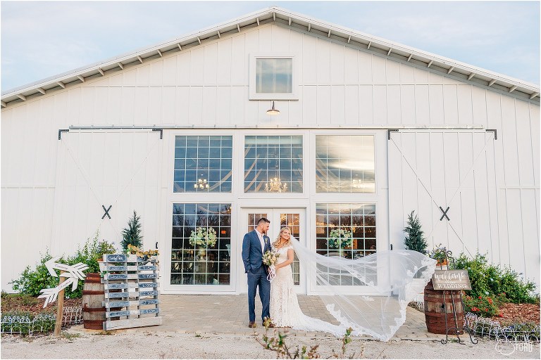 bride's veil blows in the wind in front of barn at Ever After Farms wedding