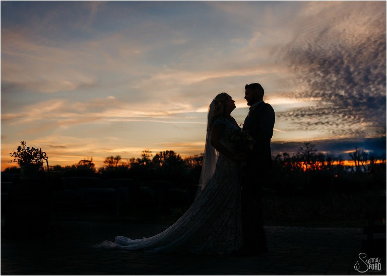 bride and groom silhouetted in front of beautiful blue and orange sunset at Ever After Farms wedding