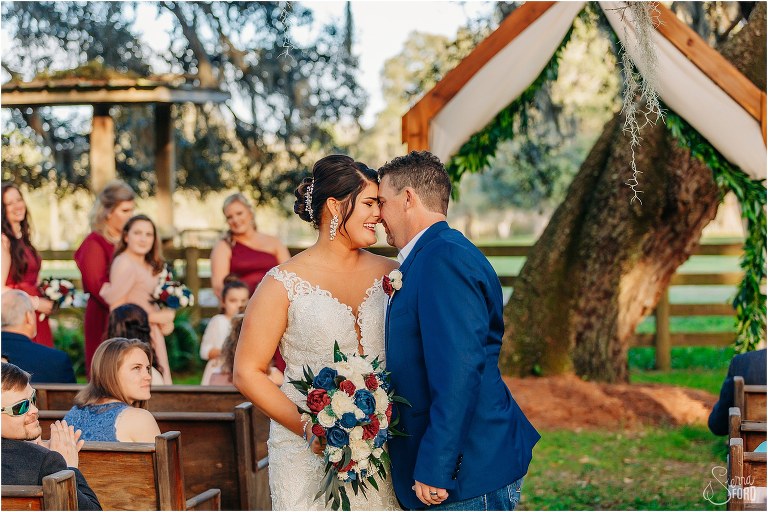 bride and groom smile forehead to forehead at end of aisle as husband and wife at Isola Farms wedding
