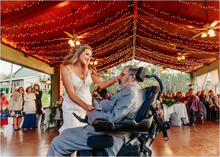 bride shares dance with her father as guests look on at lakefront wedding reception