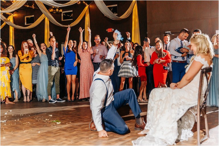 guests cheer as groom emerges victorious with garter at Ever After Farms wedding