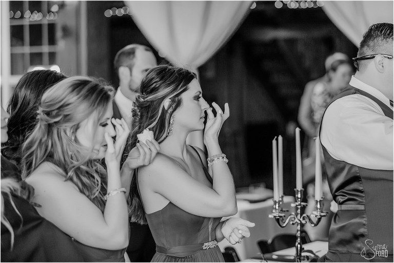 bridesmaids wipe tears away as they watch emotional father daughter dance at lakefront wedding